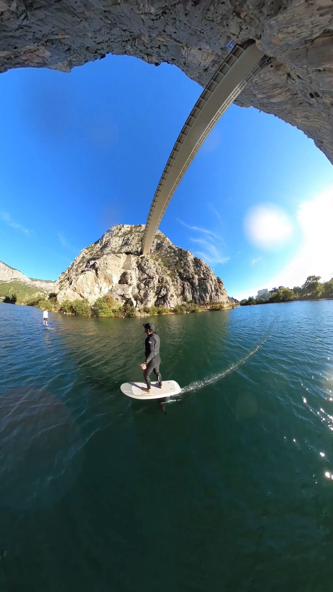 A rider stands on an eFoil on the green Cetina river under the bridge in Omiš.