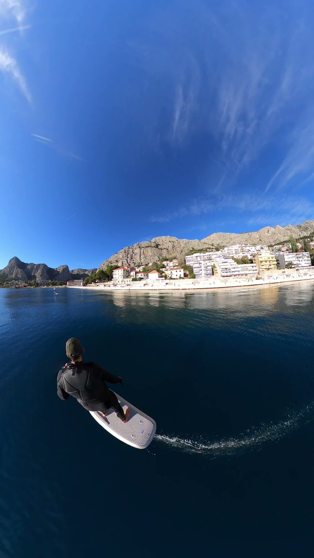 A rider carves across calm, deep-blue water in front of Omiš, its houses lining the shore beneath limestone mountains.