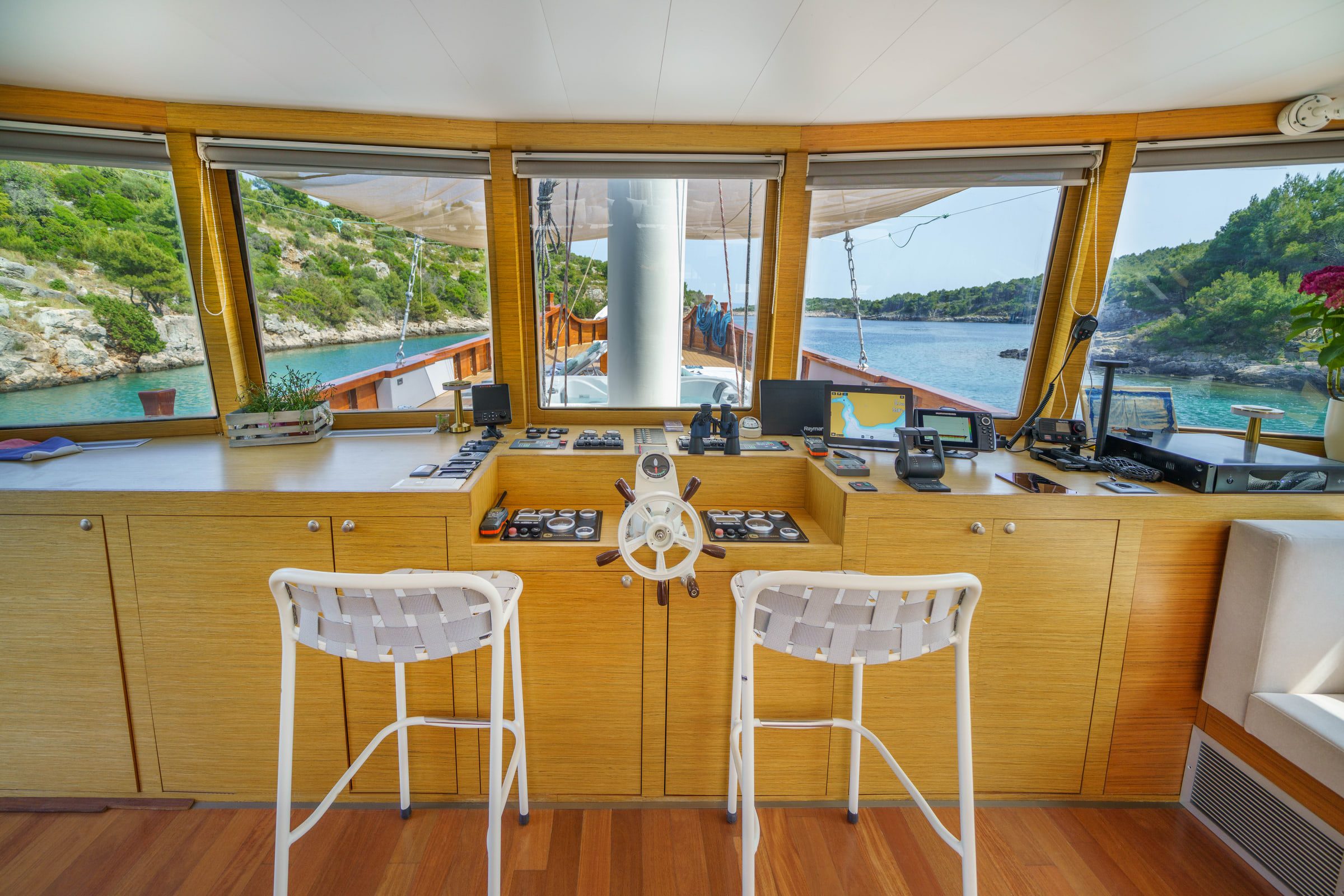 The wheelhouse with bar stools, the ship's wheel and wide windows onto the bay.